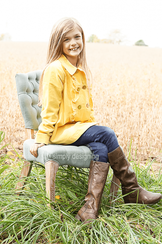 Photo of Girl in a yellow jacket, jeans and boots on Chair in Field