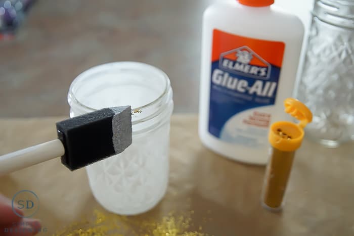 DIY Gold Glitter Mason Jar Luminaries - add glue to mason jar