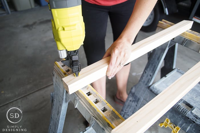 Using a Nail Gun to add a couple brad nails to hold the post boards together for the DIY Baby Gate