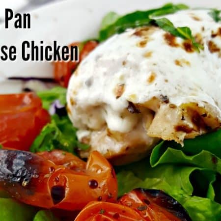 Sheet Pan Caprese Chicken - Mozzarella covered chicken on a bed of greens with blistered grape tomatoes