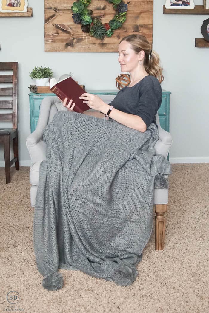 reading a book on a chair with a gray blanket