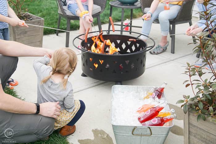 friends and family roasting hot dogs over fire pit