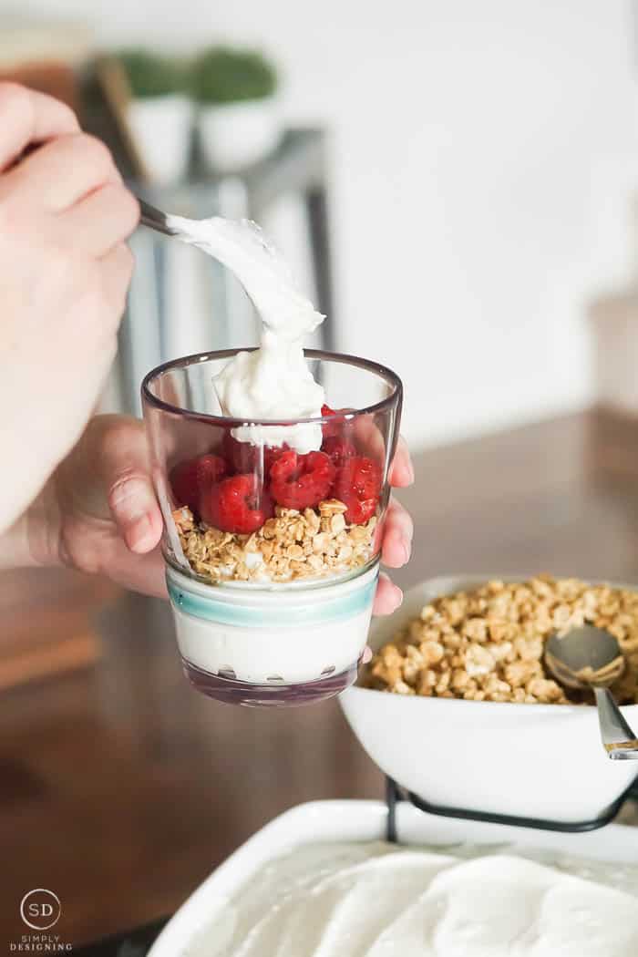 put yogurt and toppings into a glass to make a yogurt parfait