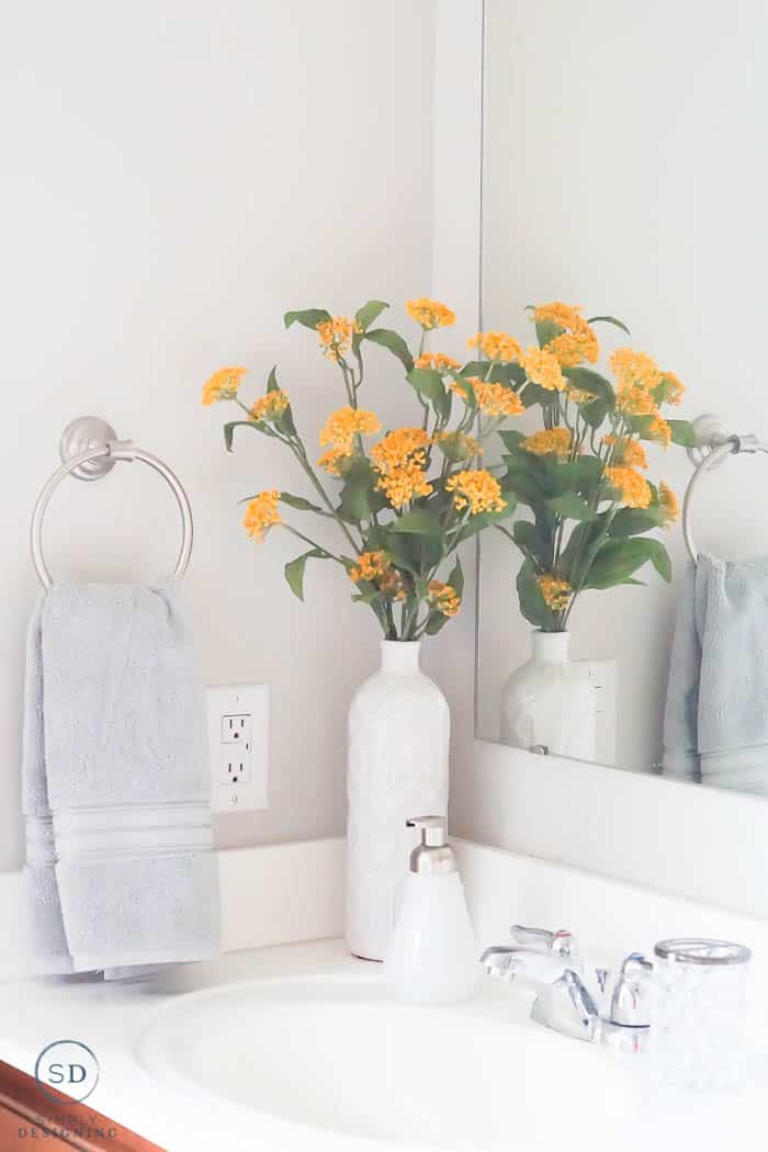 Gray hand towel and yellow flowers in a white vase