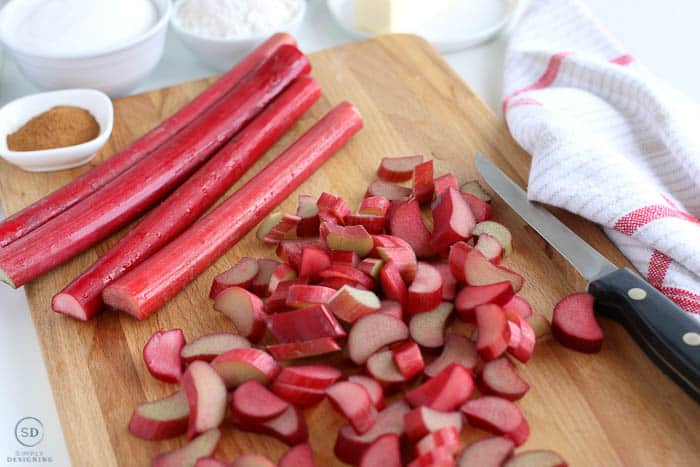 Chopped rhubarb on a cutting board with other ingredients for an easy rhubarb crisp
