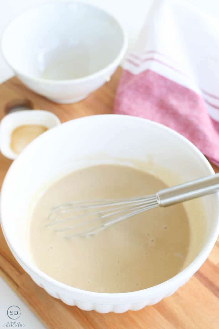 Sweetened condensed milk and vanilla extract whisked together in a bowl to make homemade ice cream.