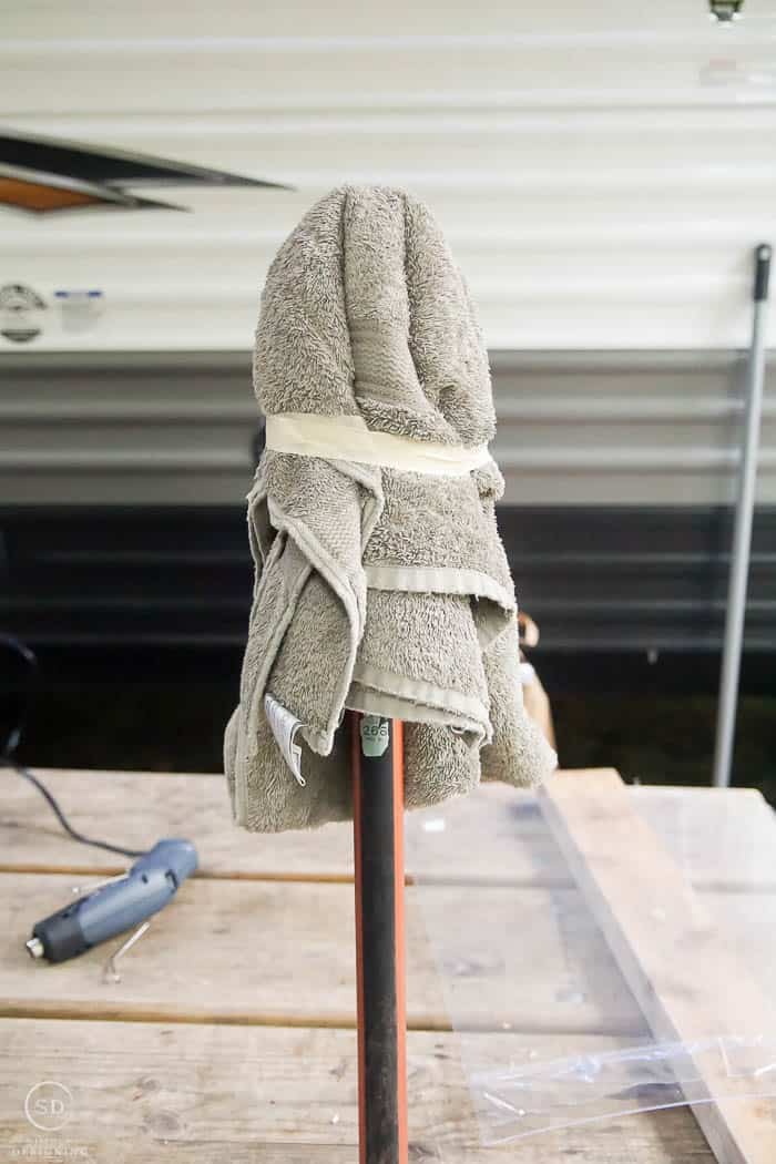 towel taped to broom handle to use as a mold for a hanging ghost lantern