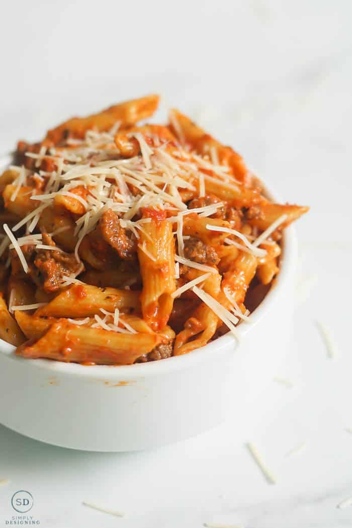 Instant pot ziti with ground beef in a white bowl on marble background