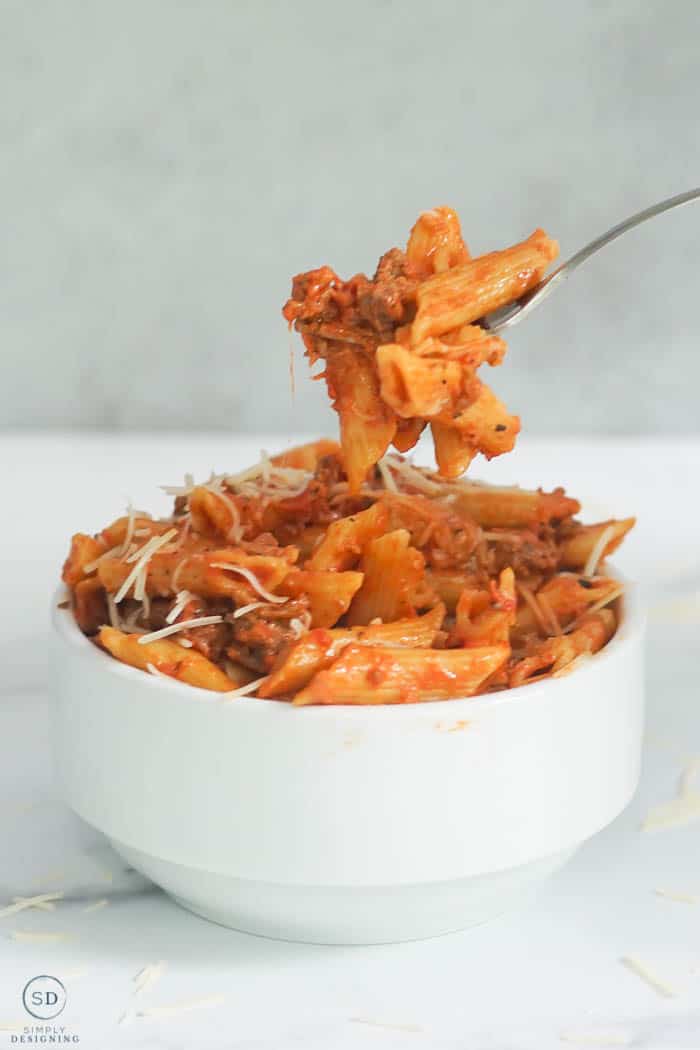 baked Instant Pot Ziti in a white bowl with a fork full being lifted up