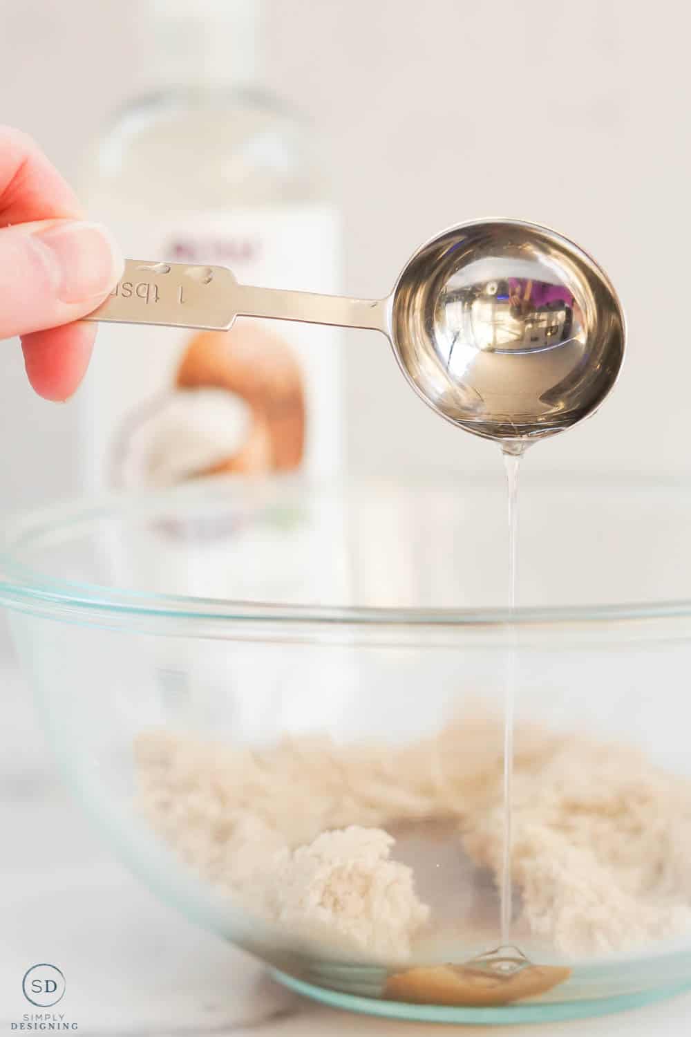 pour coconut oil into bowl with measuring spoon