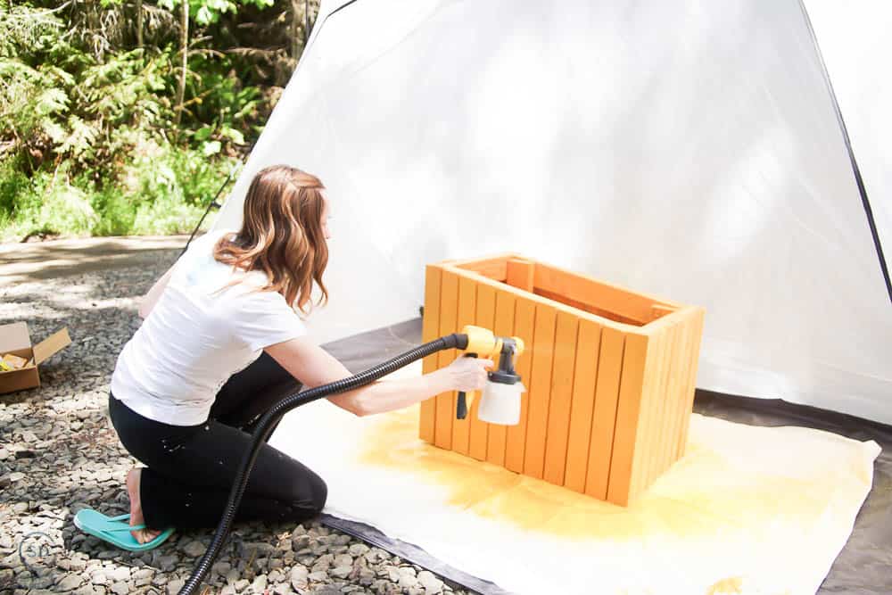 a side view of spraying stain on cat house
