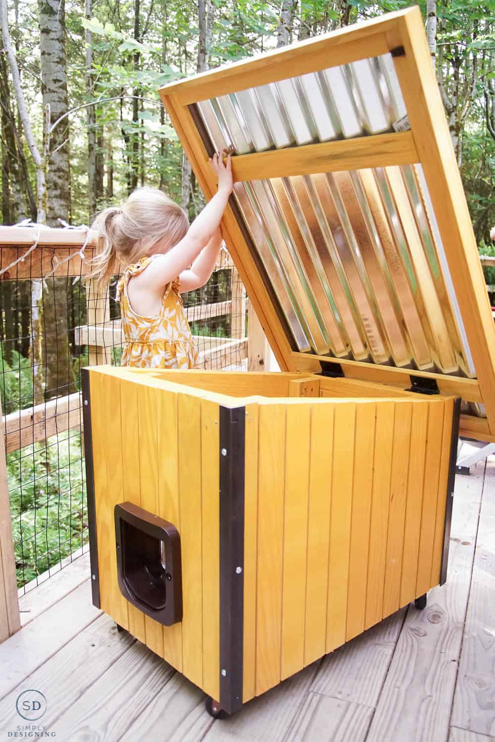 little girl opening up roof of cat house