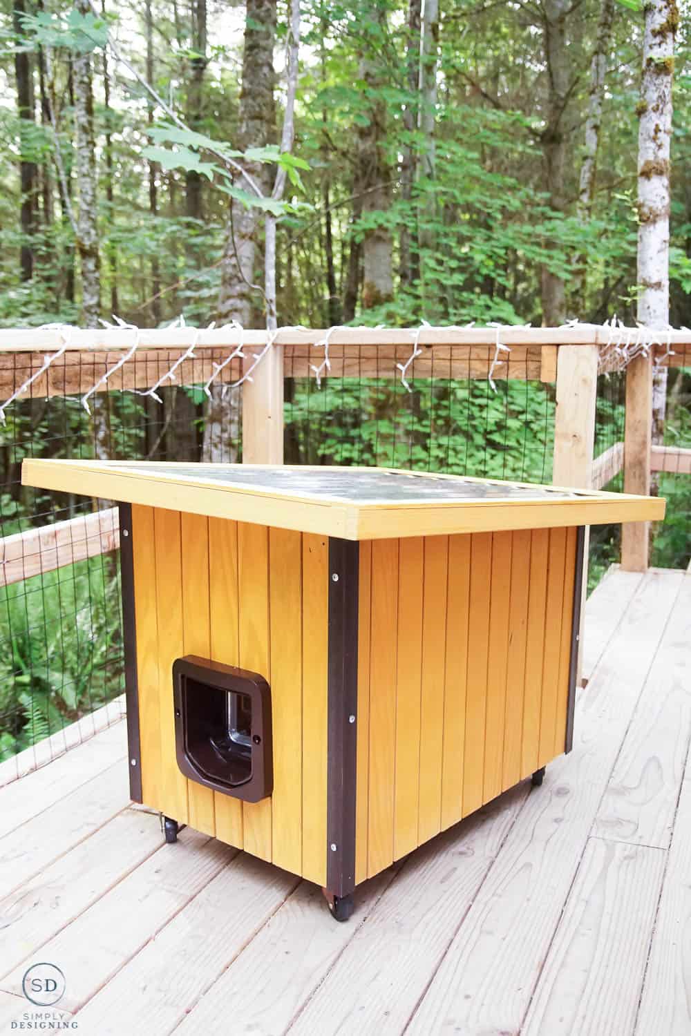 vertical photo of stained outdoor cat house with metal roof and angle iron on the sides