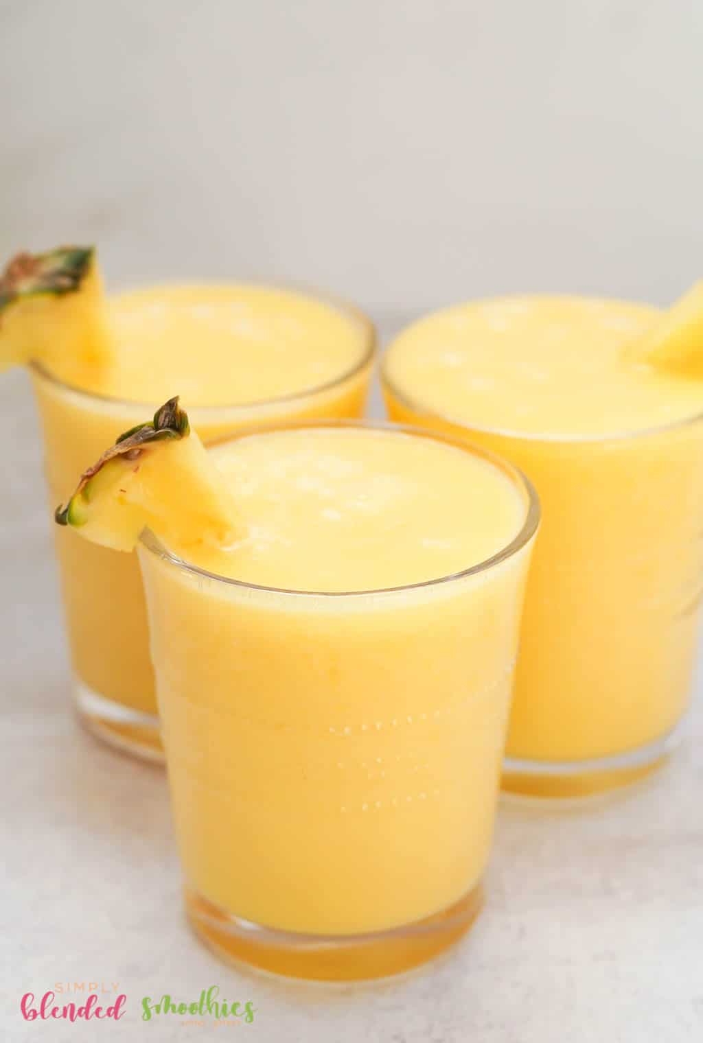 Peach Pineapple Smoothie 3 smoothie made with peaches and pineapple in clear glasses with pineapple garnish