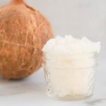 Coconut Sugar Scrub in a glass jar with a coconut in the background