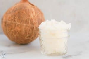 Coconut Sugar Scrub in a glass jar with a coconut in the background