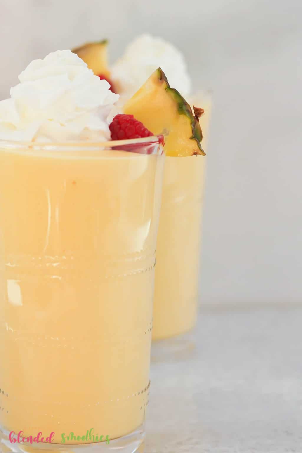 Peach Pineapple Milkshake 5 vertical photo of two milkshakes made with peaches and pineapples topped with whipped cream