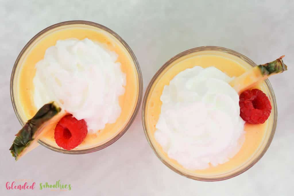 Peach Pineapple Milkshake 3 peach pineapple milkshake with whipped cream topping a raspberry and a pineapple slice looking at it from the top down