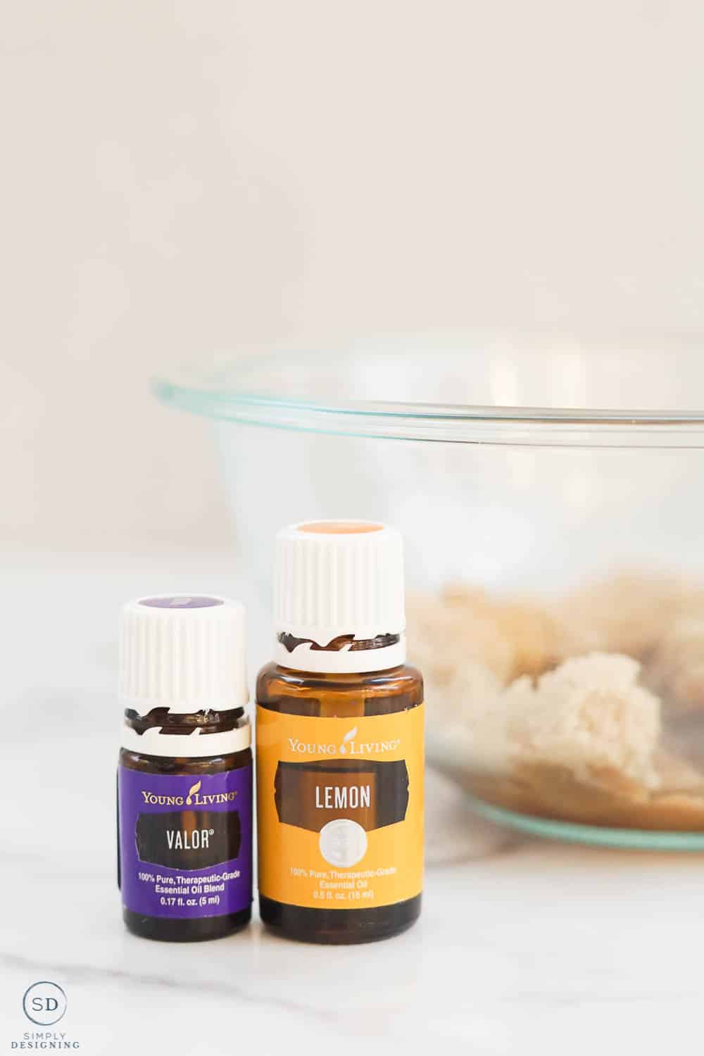 lemon and valor essential oil sitting in front of a glass bowl with brown sugar in it
