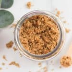 looking down on brown sugar hand scrub with greenery and a wood spoon