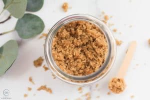 looking down on brown sugar hand scrub with greenery and a wood spoon
