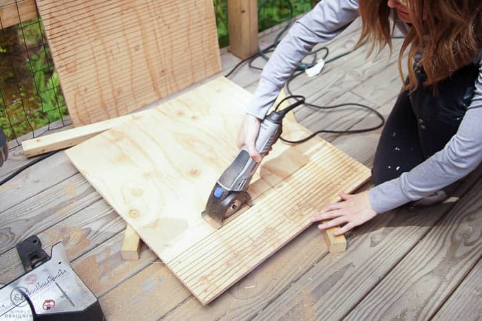 woman using dremel to cut grooves in plywood to bat house