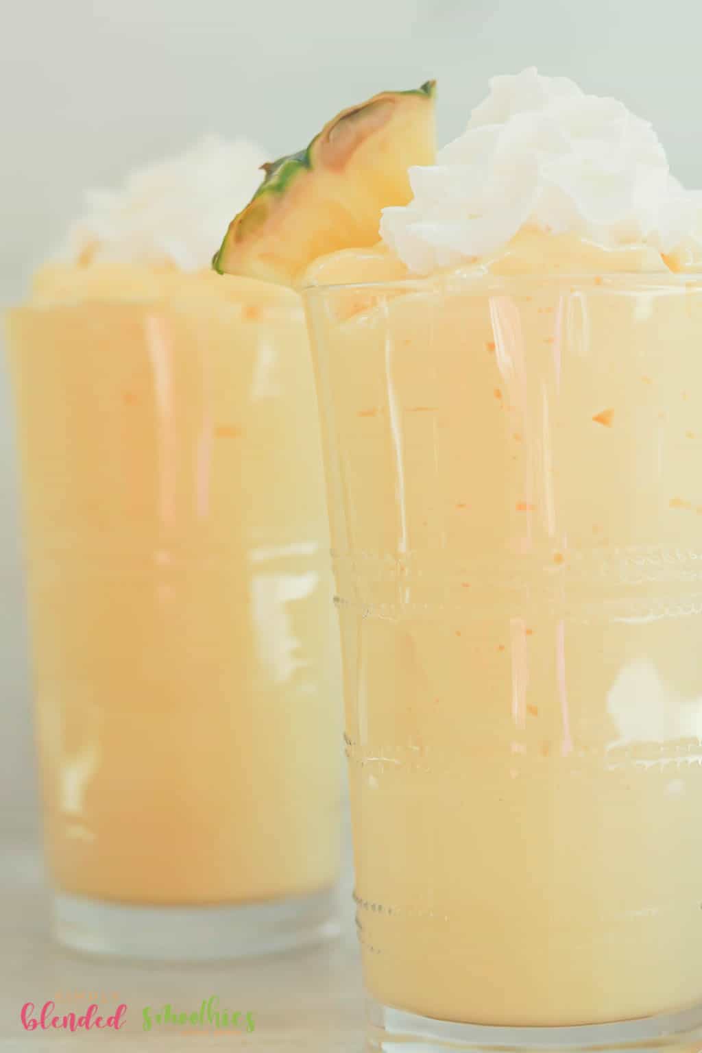 Mango Pineapple Milkshake 5 close up vertical photo of milkshake made with mangos and pineapple topped with whipped cream and a fresh pineapple slice