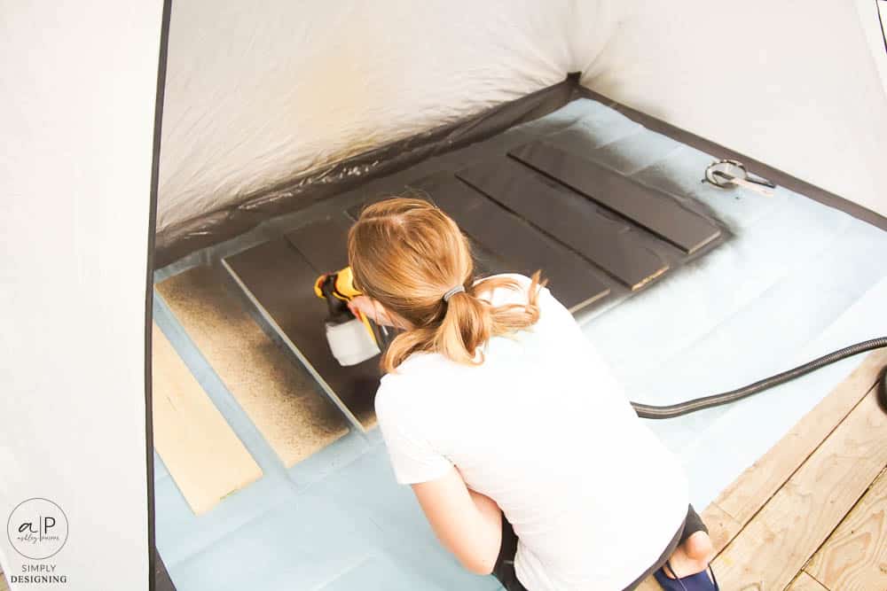 spraying stain onto wood boards in a spray shelter