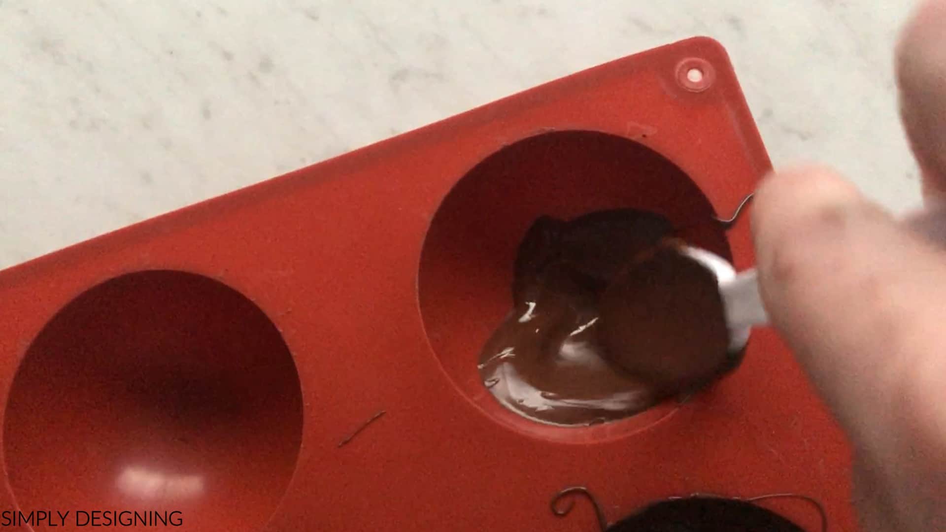 spread melted chocolate in silicone sphere mold for hot cocoa bombs