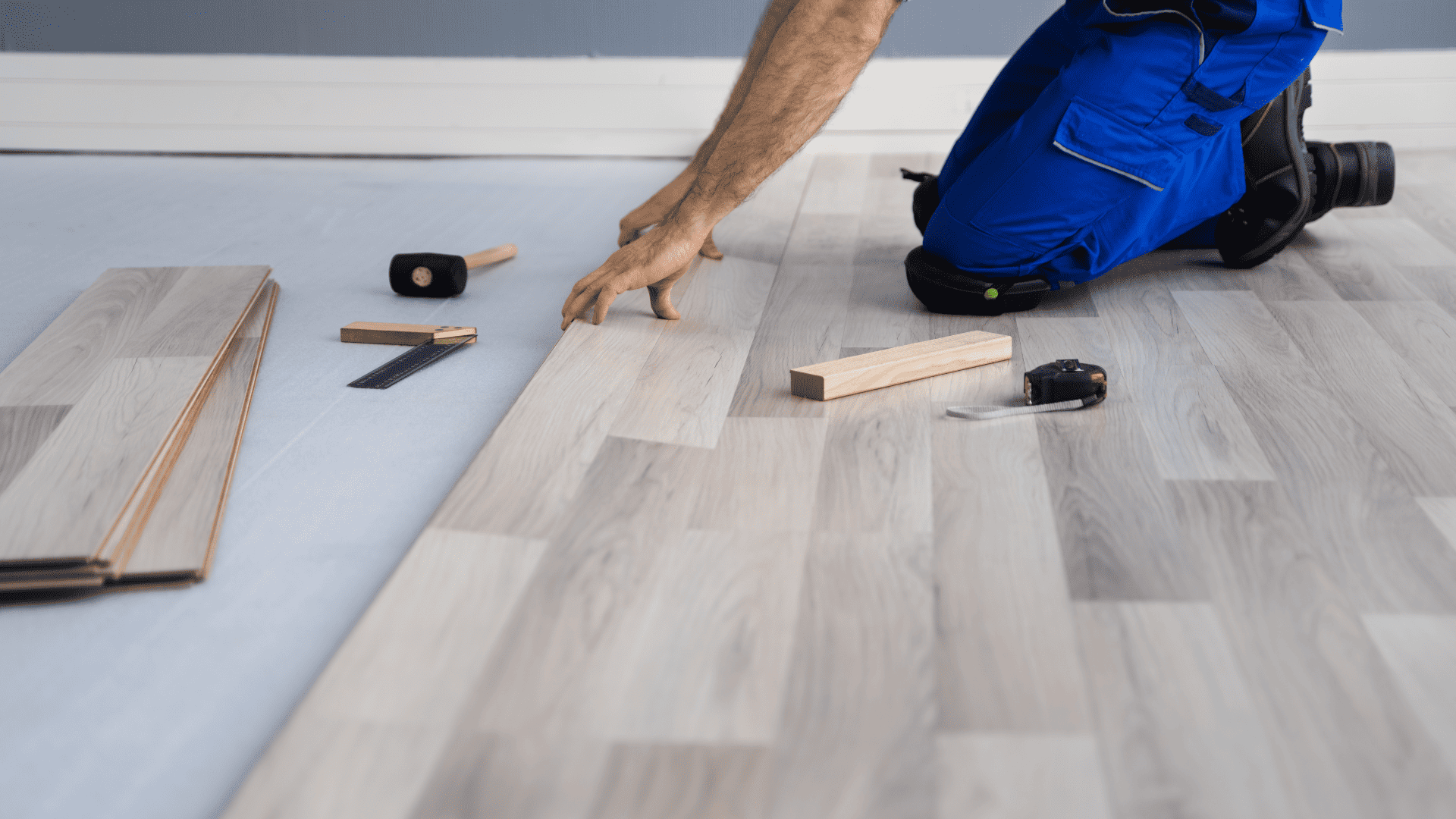 image of guy in jeans installing lvp or laminate flooring - LVP vs LAMINATE FLOORING
